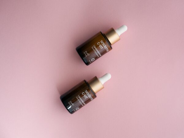 Two Sesderma C-VIT serum dropper bottles on a pastel pink surface.